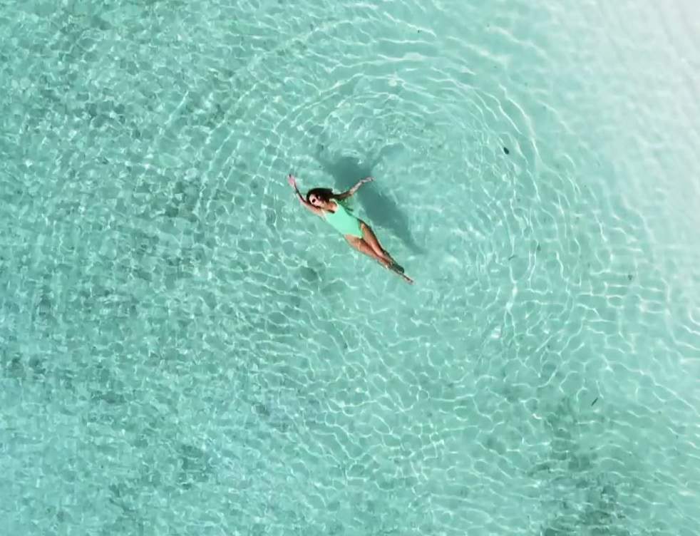 A guest floating in a clear turquoise Maldivian lagoon
